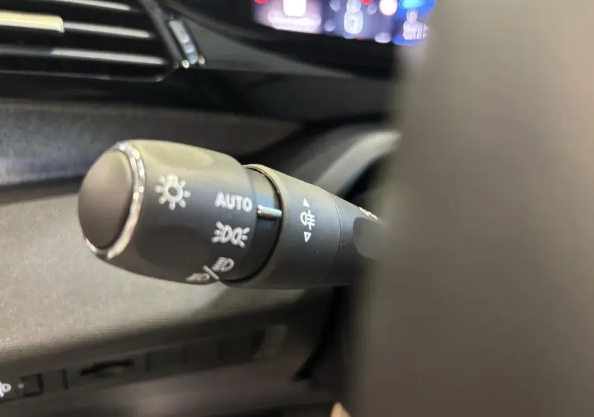 Gros plan sur la commande des feux du tableau de bord d’une Peugeot 308 SW gris clair Metal Artense 2024.