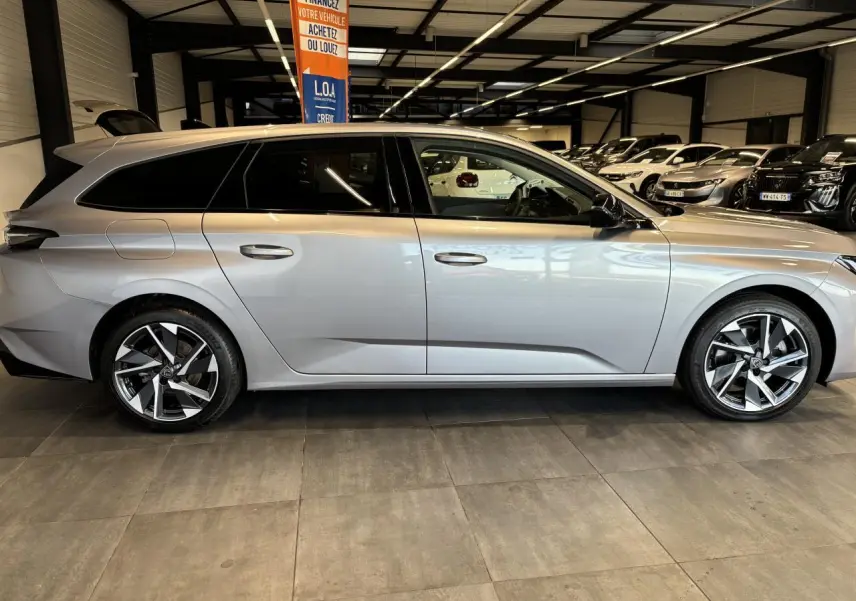 Peugeot 308 SW gris clair métal Artense vue de profil côté gauche en intérieur avec jantes alliage 17 pouces.