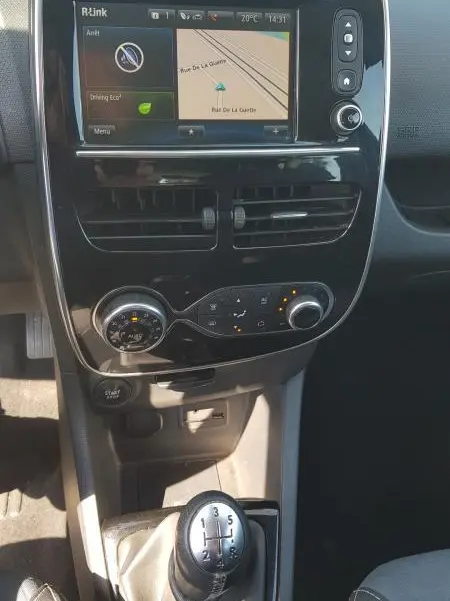 Vue intérieure centrée sur la console centrale et le levier de vitesse manuel d'une Renault Clio IV noire de 2015.