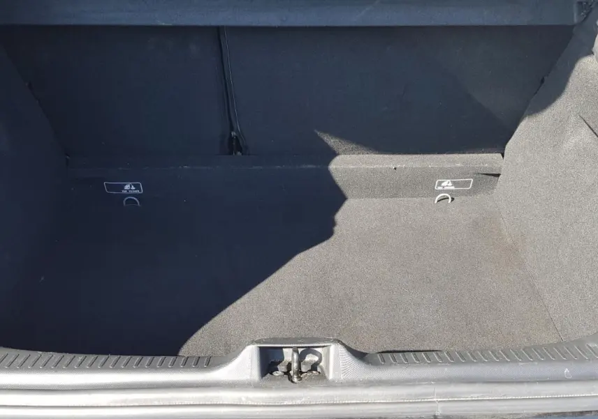 Coffre ouvert d’une Renault Clio IV dCi 90 eco2 Intens noir, montrant l’espace de chargement vide et la moquette noire.