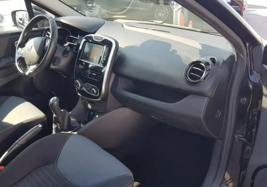 Vue intérieure côté passager de la Renault Clio IV noire, montrant tableau de bord et console centrale avec écran tactile.