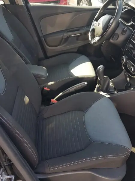 Intérieur avant droit de la Renault Clio IV dCi 90 eco2 Intens 2015 noire, sièges tissu et volant cuir visible.