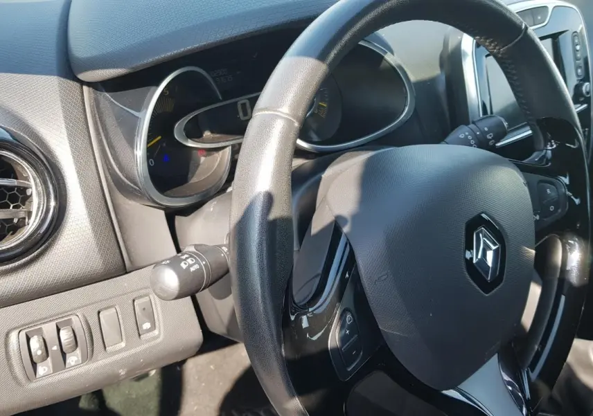 Vue rapprochée de l’intérieur de la Renault Clio IV dCi 90 Intens, volant cuir et tableau de bord noir.