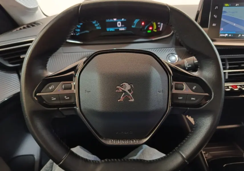 Vue rapprochée du volant cuir noir de la Peugeot 208 électrique Active Business avec tableau de bord digital allumé.