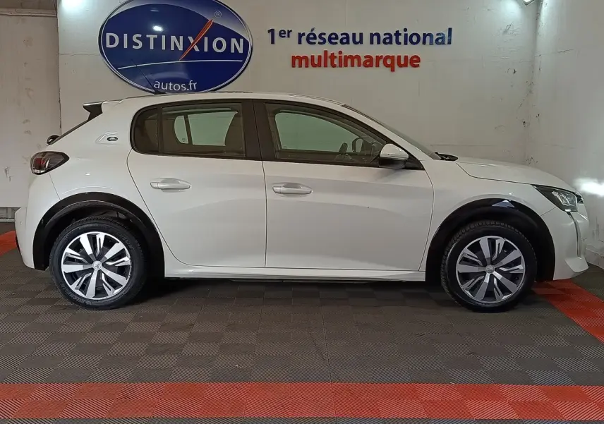 Profil droit d'une Peugeot 208 Electrique Active Business blanche, avec jantes distinctives et logo "e" sur l'aile arrière.