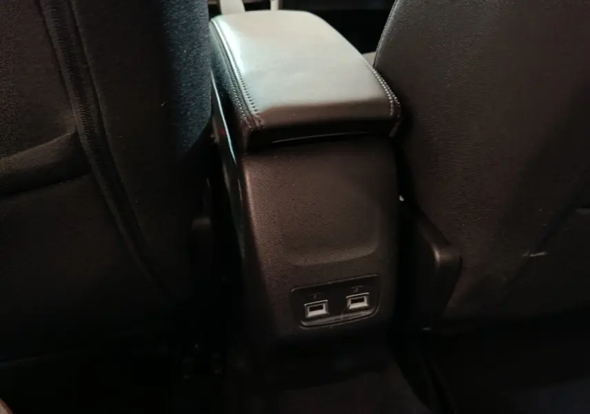Vue rapprochée de la console centrale arrière avec accoudoir noir et deux ports USB dans une Peugeot 208 blanche électrique.