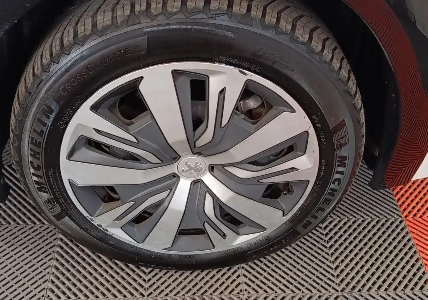 Gros plan sur la roue avant droite d’une Peugeot 208 électrique blanche, jante alliage au design moderne.