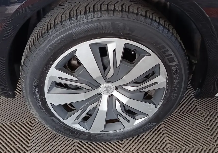 Gros plan sur la roue avant droite de la Peugeot 208 électrique blanche, avec jante en alliage au design moderne.