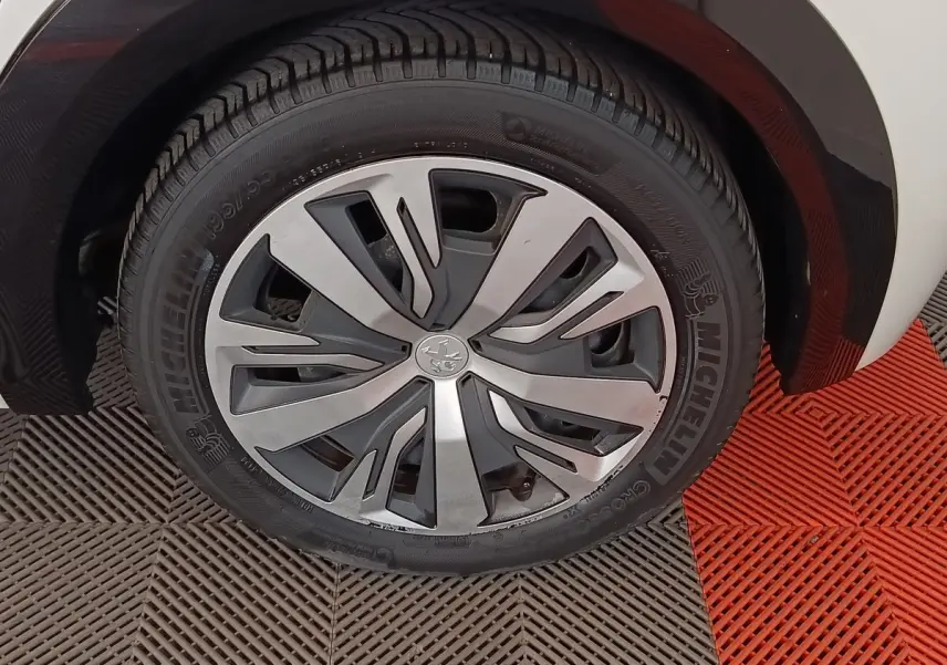 Gros plan sur la roue avant droite de la Peugeot 208 Electrique Active Business blanche, jante alliage moderne.