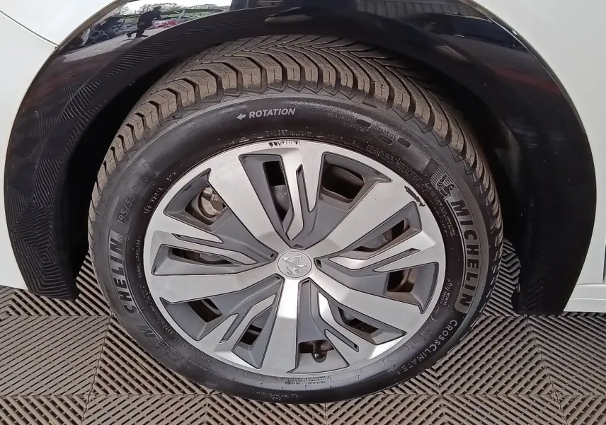 Gros plan sur la roue avant droite de la Peugeot 208 électrique blanche, avec jante en alliage et pneu Michelin.