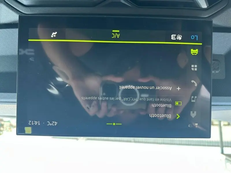 Écran tactile central du Dacia Duster blanc 2025 affichant les options Bluetooth et climatisation, vue intérieure rapprochée.