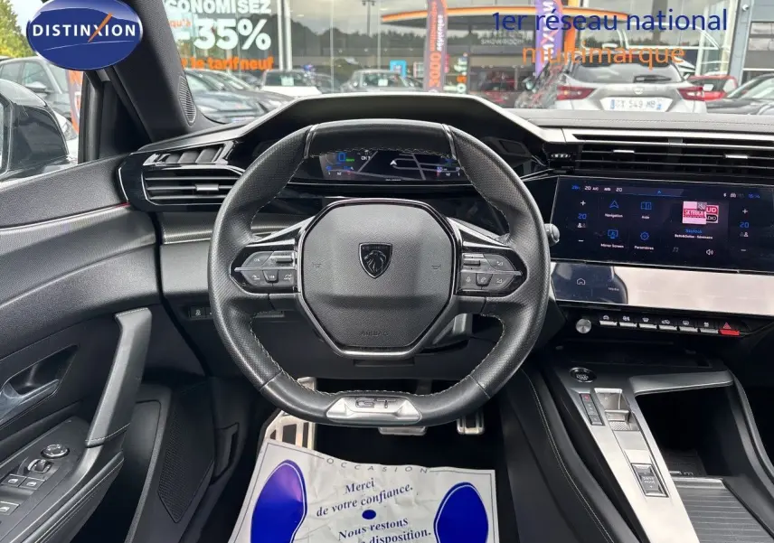 Vue intérieure centrée sur le volant cuir GT et le tableau de bord numérique de la Peugeot 308 SW hybride 2022.