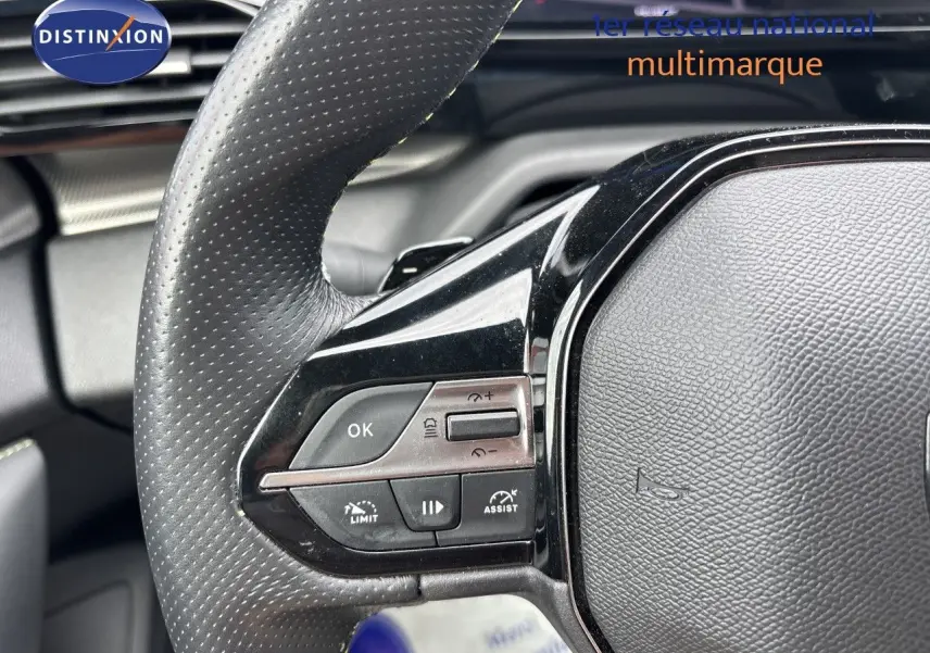 Gros plan sur le volant en cuir perforé côté gauche du Peugeot 308 SW blanc nacré, avec commandes intégrées.