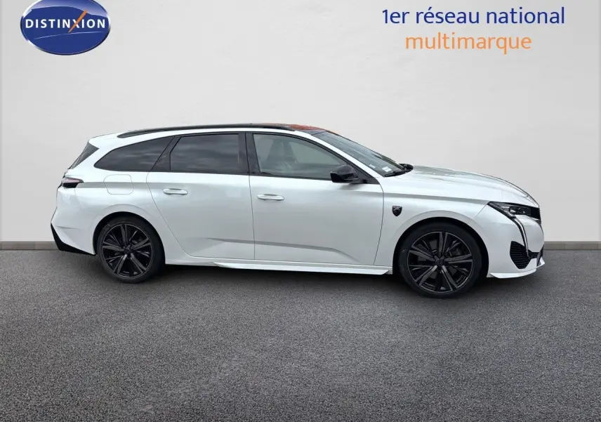 Peugeot 308 SW hybride blanc nacré, vue de profil côté gauche, jantes noires et vitres teintées.