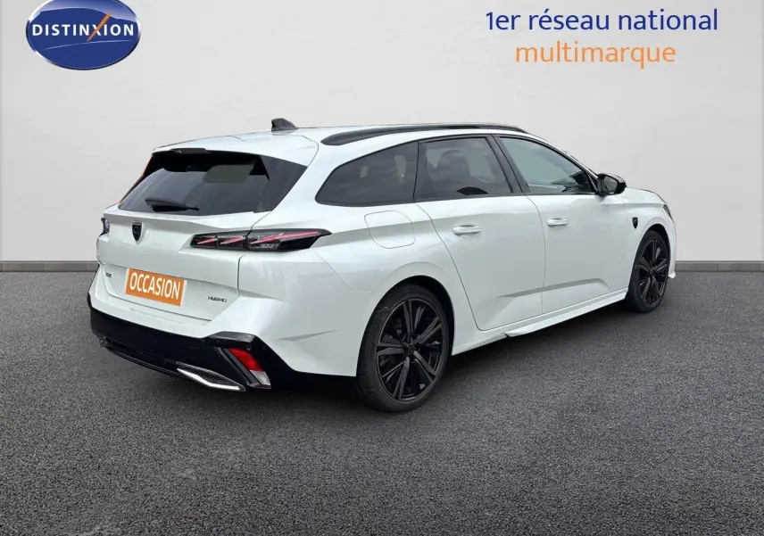 Peugeot 308 SW hybride blanc nacré, vue 3/4 arrière droit, jantes noires et feux arrière LED distinctifs.