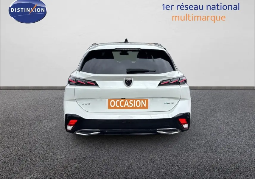 Vue arrière d'une Peugeot 308 SW hybride blanche nacrée avec feux LED et double sortie d'échappement chromée.