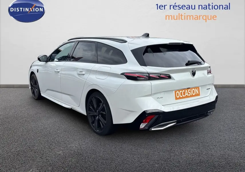 Peugeot 308 SW hybride blanc nacré, vue 3/4 arrière droit, jantes noires et feux arrière LED distinctifs.