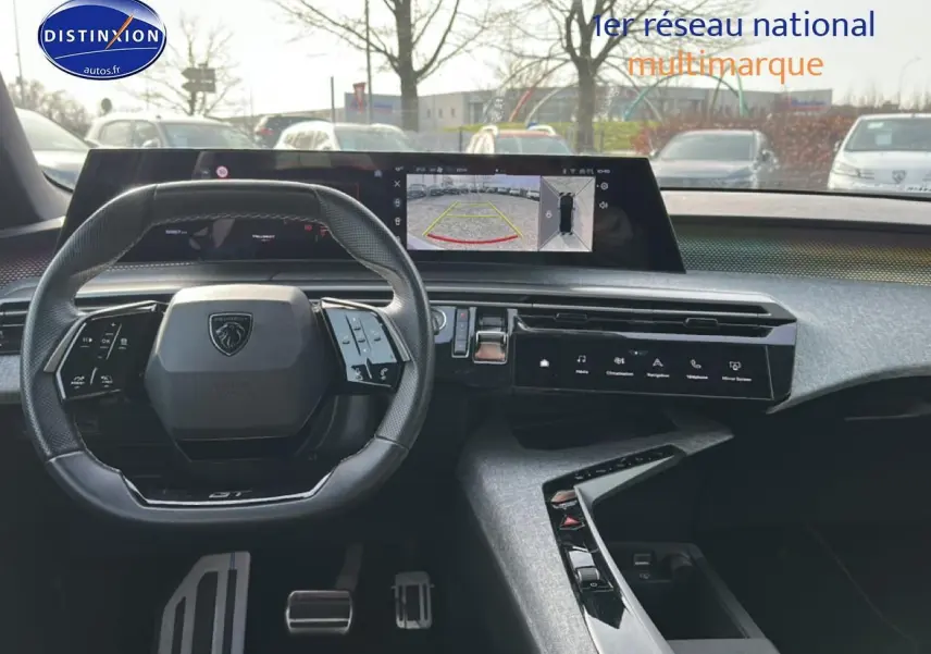 Vue intérieure frontale du tableau de bord et volant cuir noir du Peugeot 3008 gris Artense, avec écran tactile et caméra de recul affichée.