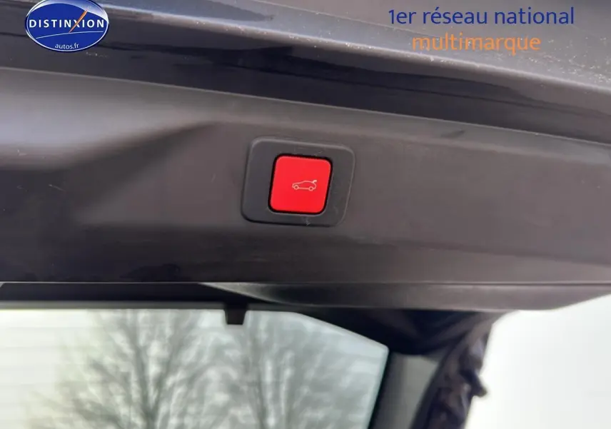Bouton rouge d'ouverture électrique du coffre sur la partie intérieure du hayon d'un Peugeot 3008 gris Artense.