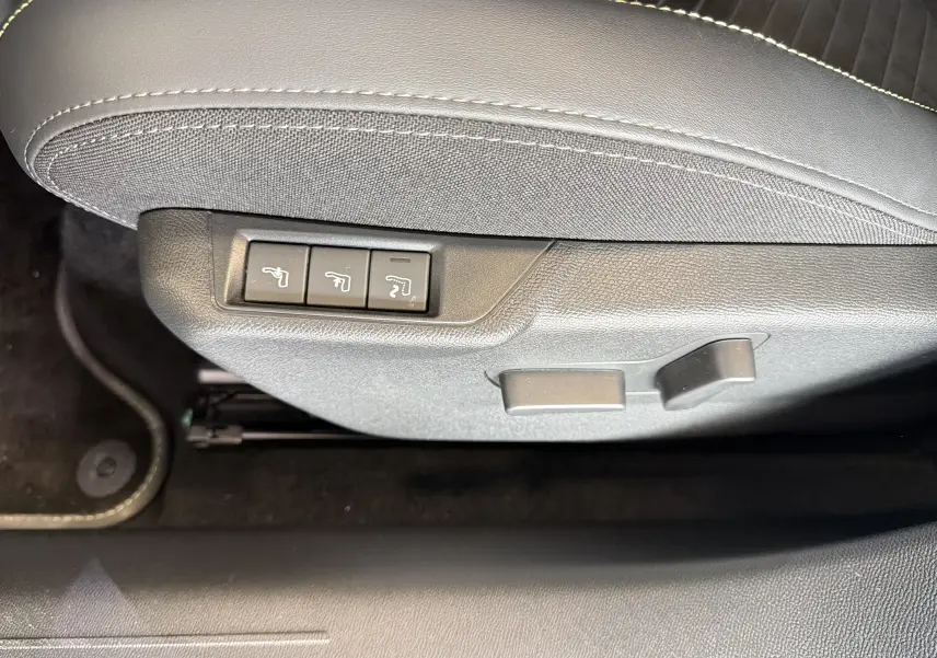 Détail des commandes de réglage électrique du siège avant en sellerie Alcantara noir sur Peugeot 208 Hybrid 145 GT.