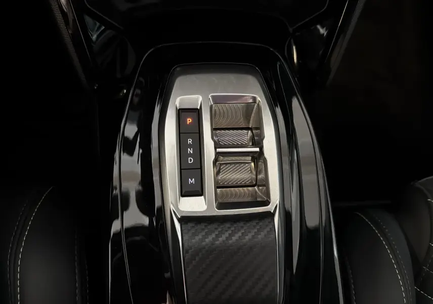 Gros plan sur la console centrale noire brillante de la Peugeot 208 HYBRID 145 e-DCS6 GT avec levier de vitesses électronique.