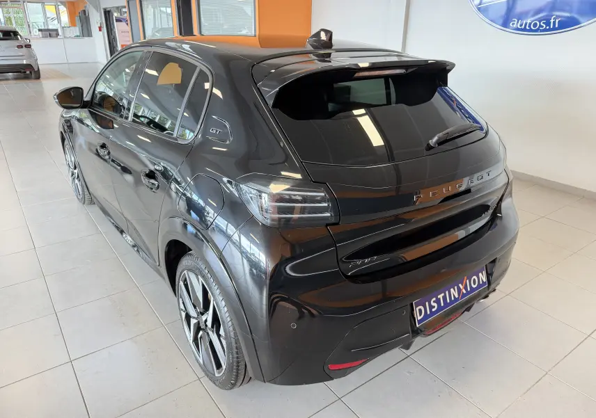 Peugeot 208 Hybrid 145 GT noir perla vue 3/4 arrière droit en intérieur avec jantes alliage 17 pouces bicolores.