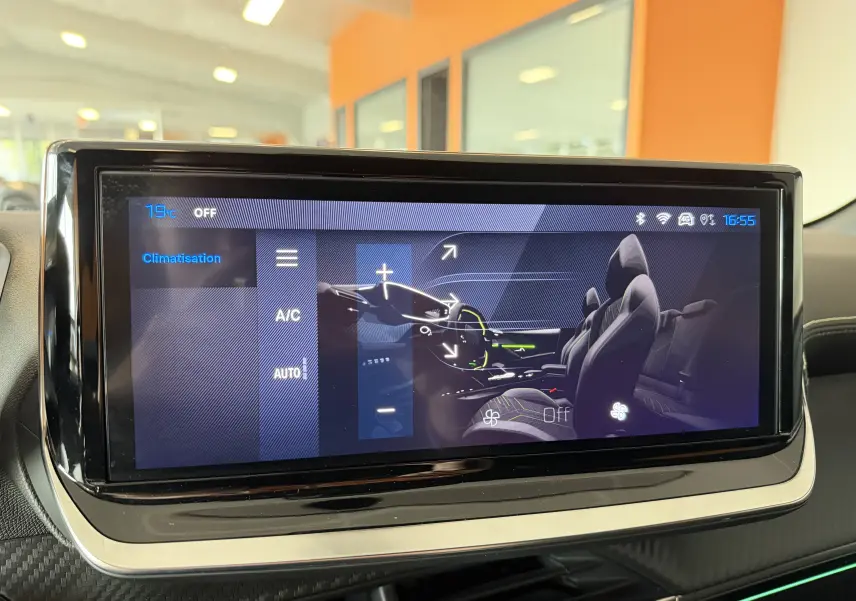 Écran tactile intérieur de la Peugeot 208 Hybrid 145 GT montrant la commande de climatisation et sièges en Alcantara noir.