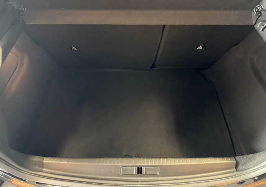 Coffre vide vu de dessus d'une Peugeot 208 Hybrid 145 e-DCS6 GT noir Perla, intérieur tissu noir.