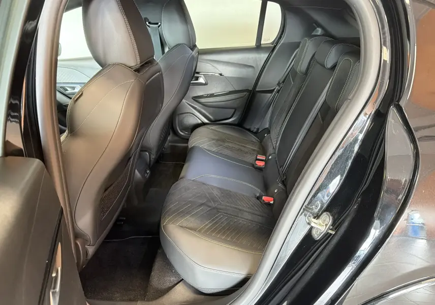 Vue intérieure côté droit sur les sièges arrière en Alcantara noir avec surpiqûres vertes d'une Peugeot 208 HYBRID 145 e-DCS6 GT noir perla.