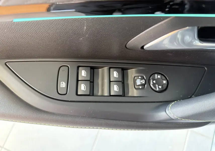 Détail de la commande des vitres et réglages des rétroviseurs sur la porte côté gauche d’une Peugeot 208 Hybrid 145 GT noire.