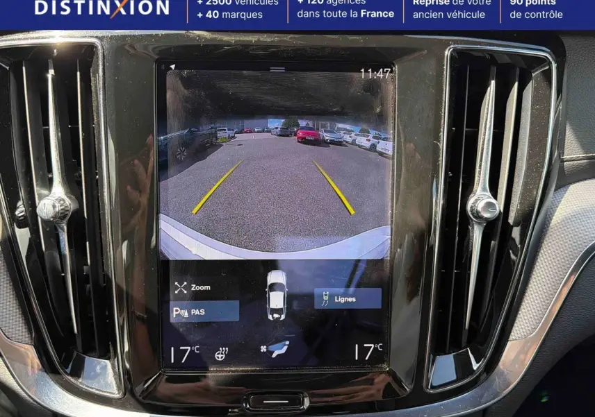 Écran central tactile montrant la caméra de recul d'une Volvo S60 blanche, avec aérateurs latéraux chromés.