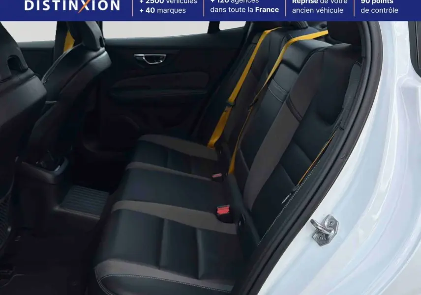 Vue intérieure côté arrière droit d'une Volvo S60 blanche, sièges arrière en cuir noir avec ceintures jaunes dorées.