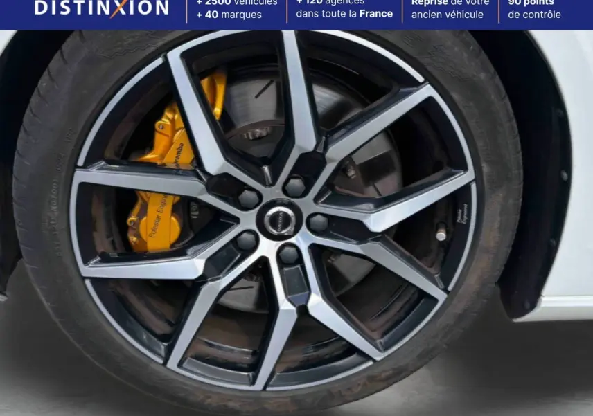 Gros plan sur la jante alliage 19 pouces bicolore et étrier de frein jaune Polestar d'une Volvo S60 blanche.