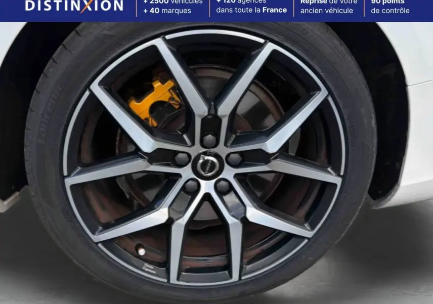Gros plan sur la jante alliage 19 pouces style Y noir et argent avec étrier de frein jaune sur Volvo S60 blanche.