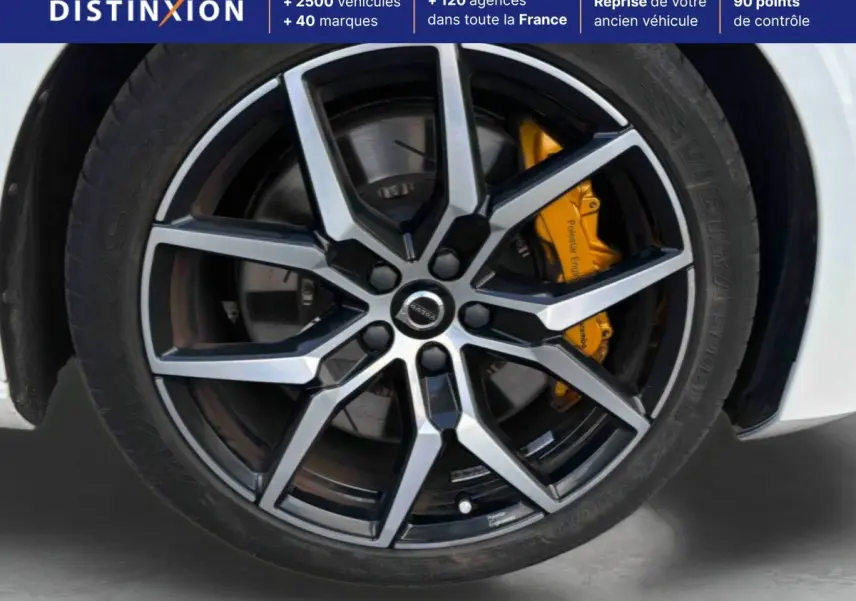 Gros plan sur la jante alliage 19 pouces noir et argent de la Volvo S60 blanche avec étrier de frein jaune Polestar Engineered.