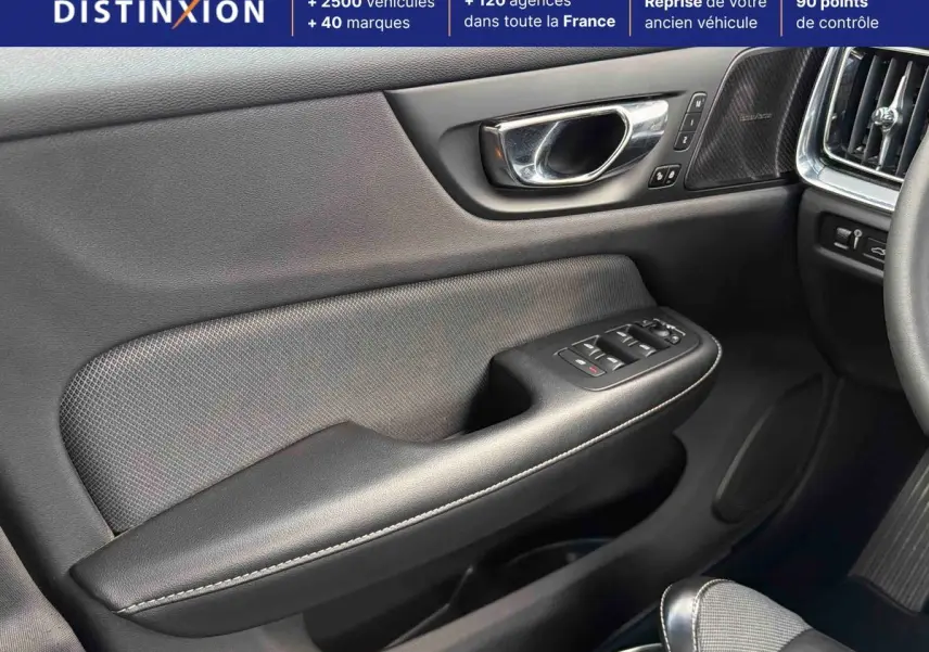 Détail de la porte avant gauche intérieure d’une Volvo S60 blanche, avec commandes de vitres et insert haut-parleur Harman Kardon.