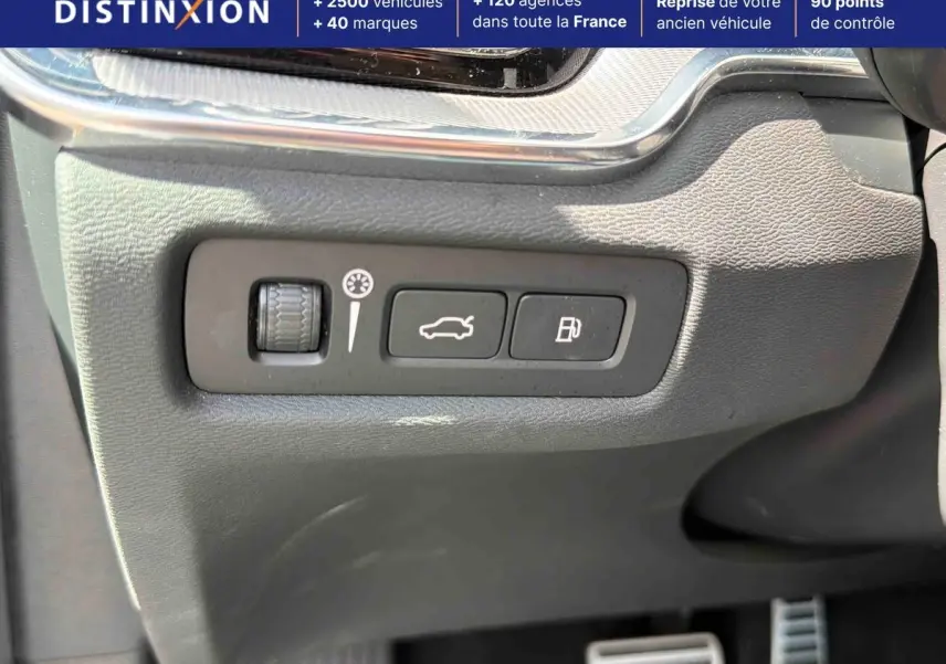 Gros plan sur les commandes d'ouverture du coffre et de la trappe à carburant dans l'habitacle d'une Volvo S60 blanche.