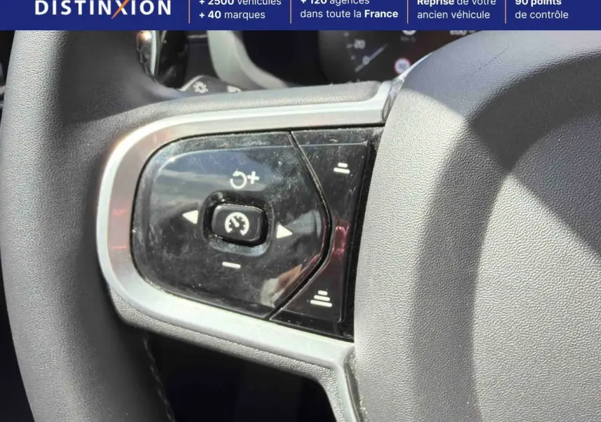 Gros plan sur les commandes de régulateur de vitesse au volant d'une Volvo S60 blanche, intérieur lumineux.