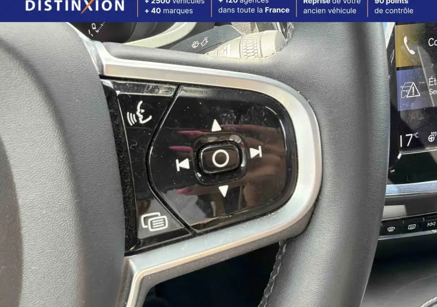Gros plan sur les commandes vocales et multimédia au volant d'une Volvo S60 blanche, intérieur moderne avec écran tactile visible.
