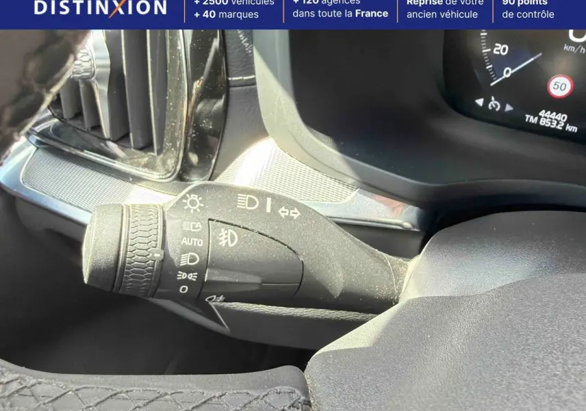 Gros plan sur la commande des feux à gauche du volant dans l’habitacle du Volvo S60 blanc de 2021.