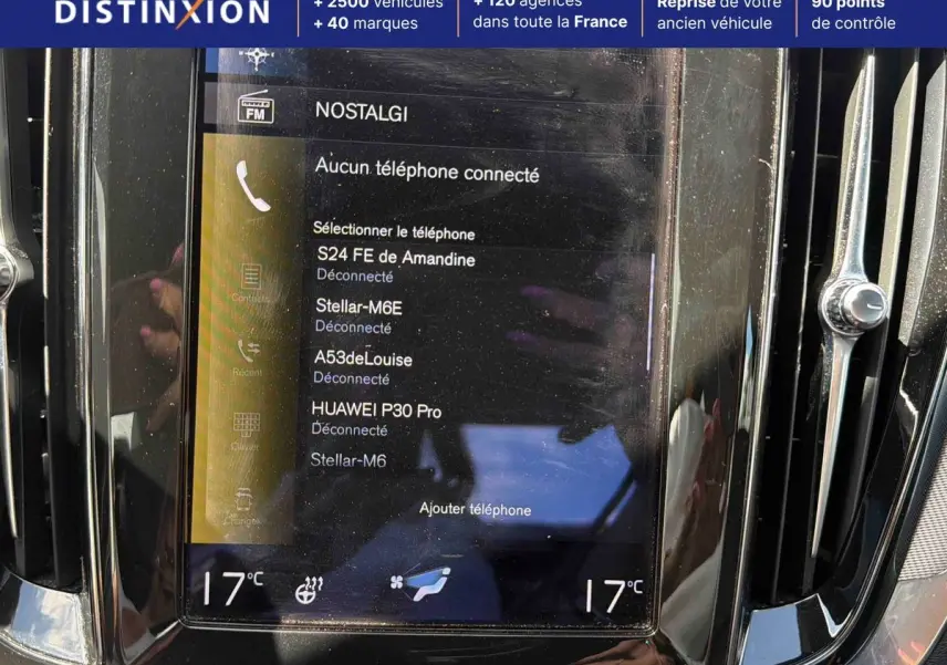 Vue rapprochée de l’écran tactile central noir de la Volvo S60 blanche, affichant la connexion Bluetooth et la température à 17°C.