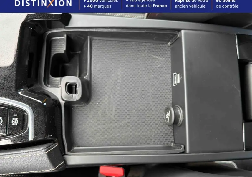 Vue rapprochée de la console centrale noire du Volvo S60 T8 blanc, avec levier de vitesses manuel et rangement ouvert.