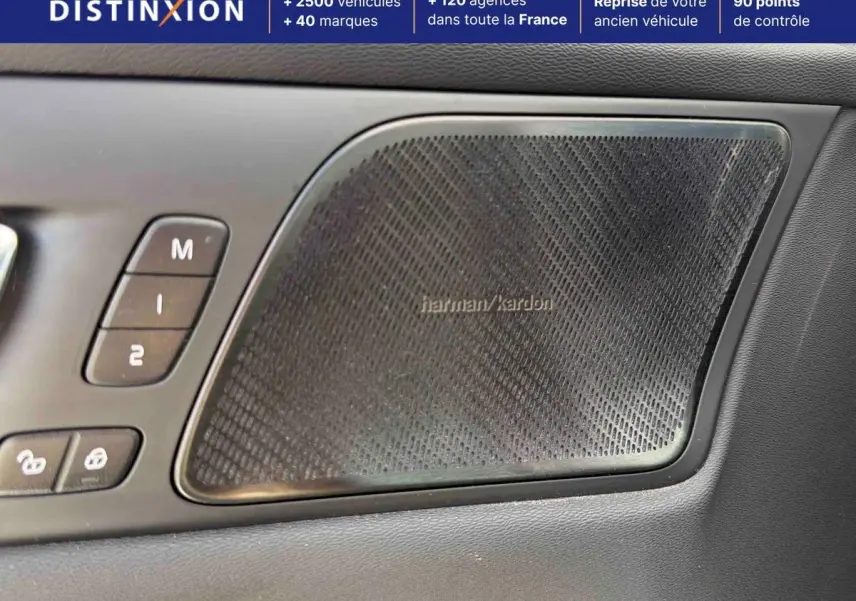 Détail du haut-parleur Harman Kardon et commandes de porte côté conducteur d’une Volvo S60 blanche.