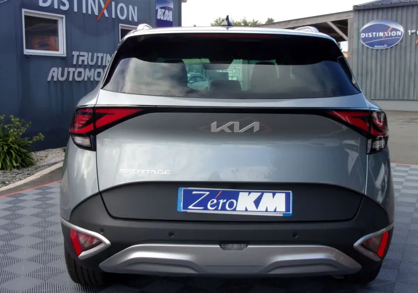 Vue arrière d'un KIA SPORTAGE gris perle 2025 avec feux arrière LED et logo KIA moderne visible.