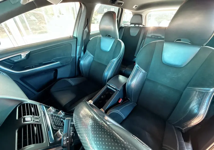 Vue intérieure avant du Volvo XC60 gris 2016 montrant sièges sport en cuir noir et console centrale.