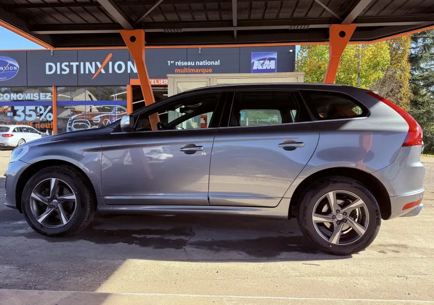 Profil côté gauche du Volvo XC60 gris 2016, version D4 Momentum avec jantes alliage et vitres teintées.
