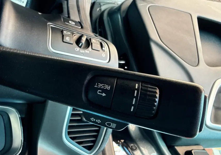 Gros plan sur la commande de réinitialisation au volant du Volvo XC60 gris, intérieur moderne et épuré visible en arrière-plan