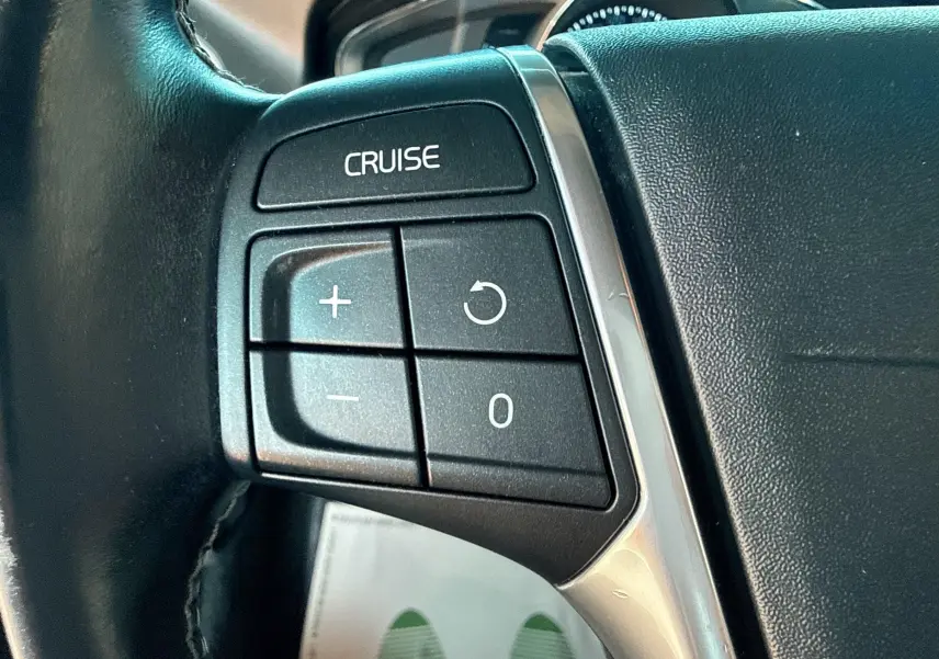 Gros plan sur les commandes de régulateur de vitesse au volant noir du Volvo XC60 gris 2016 D4 Momentum.