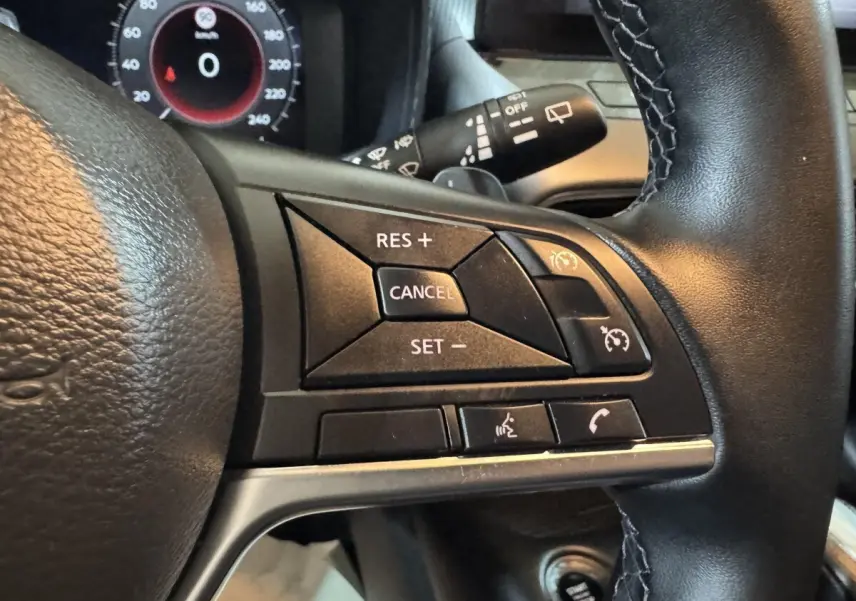 Gros plan sur le côté droit du volant cuir alu du Nissan Juke gris clair, avec commandes de régulateur de vitesse et appels.