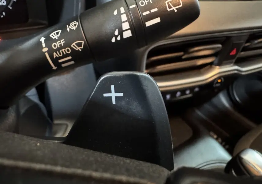 Gros plan sur la palette de changement de vitesse droite noire dans l'habitacle gris du Nissan Juke 2025.